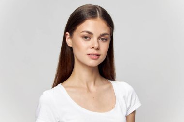 Beyaz tişörtlü güzel esmer kız izole bir arka planda ileriye bakıyor. 