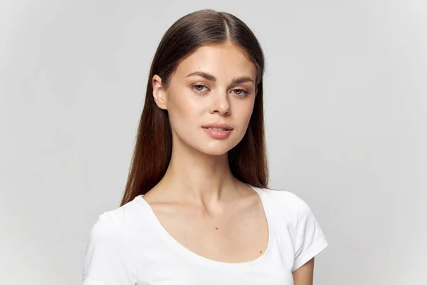 Piękna brunetka dziewczyna w białym t-shirt patrzy przed siebie na odosobnionym tle zbliżenie — Zdjęcie stockowe