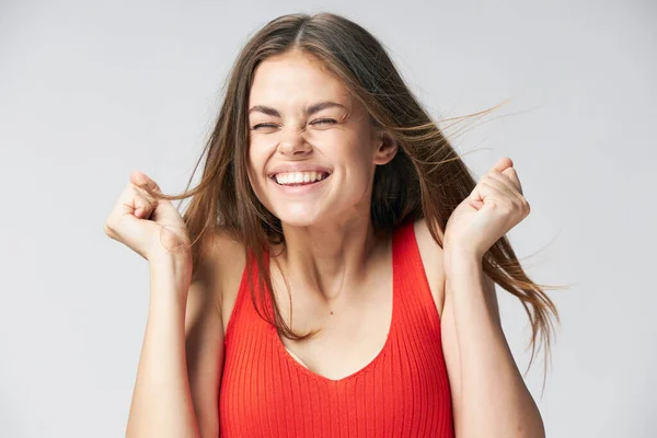 Ευτυχισμένη γυναίκα γελάει σε ένα ελαφρύ φόντο σε ένα κόκκινο μπλουζάκι — Φωτογραφία Αρχείου