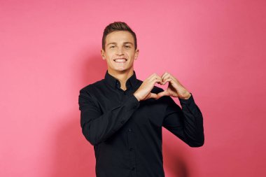 Siyah gömlekli adam el hareketleriyle yaşam tarzını pembe izole bir arkaplan.