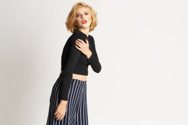 Siyah kazaklı, çizgili pantolonlu, güzel bir kadın. Moda kıyafetleri arka planda.