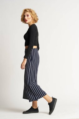 Siyah kazaklı, çizgili pantolonlu, güzel bir kadın. Moda kıyafetleri arka planda.