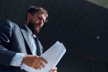 İş adamı dışarıda elinde belgelerle resmi bir yaşam tarzı inşa ediyor.