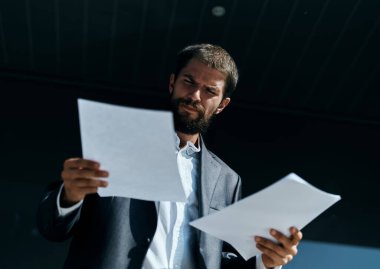 İş adamı dışarıda elinde belgelerle resmi bir yaşam tarzı inşa ediyor.