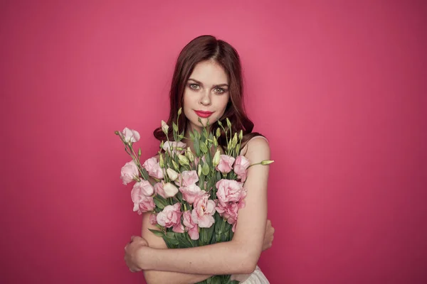 ピンクの背景をしたピンクのドレスメイクモデルの花束を持つ美しい女性 — ストック写真