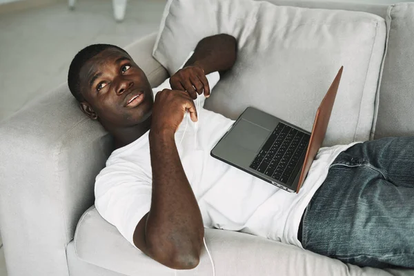 Чоловік лежить на дивані перед роботою ноутбука — стокове фото