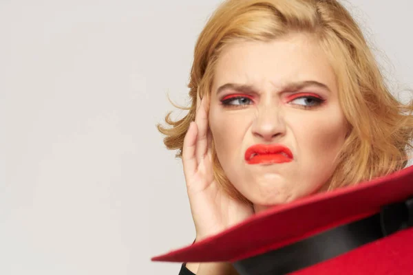 Nette blonde kurzhaarige rote Mütze in der Hand Nahaufnahme Licht Hintergrund — Stockfoto