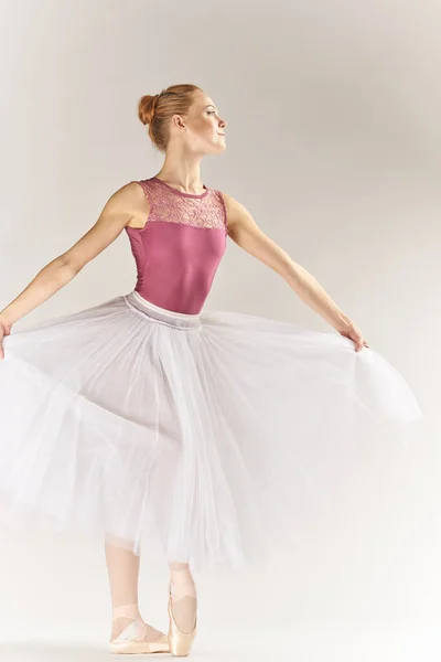 穿着尖皮鞋和浅色背景裙的女芭蕾舞演员摆出假腿跳舞的姿势 — 图库照片