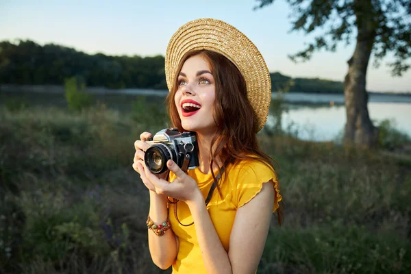 Mulher com uma câmera olha para cima em um chapéu lábios vermelhos boca aberta natureza — Fotografia de Stock