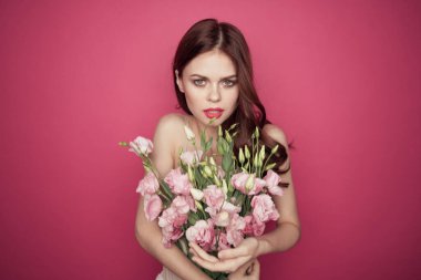 Pembe arka planda çiçekli güzel bir kadın. Açık renk bir makyaj modeli.