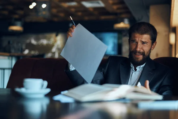 Uomo d'affari seduto a un tavolo in un caffè documenti di lavoro tazza di caffè ufficiale — Foto Stock