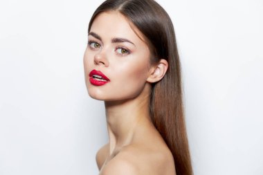 Parlak makyajlı kadın ileriye, kırmızı dudaklara, saf cilde, doğa ışığına bakar. 