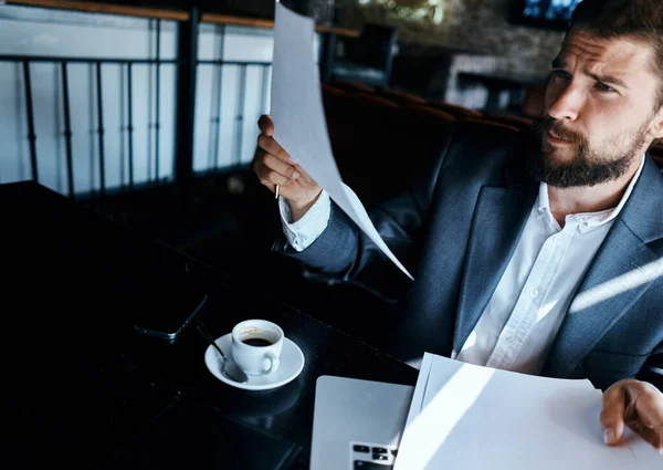 Homem de negócios em um terno de café na frente de emoções laptop tecnologia documentos oficiais — Fotografia de Stock