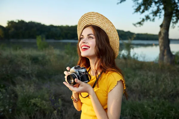 Perempuan di alam fotografer kamera di tangan tersenyum memandang topi — Stok Foto
