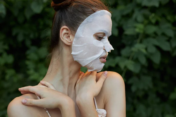 Leuke vrouw In de natuur aanraking schouders met handen cosmetisch masker cosmetologie — Stockfoto