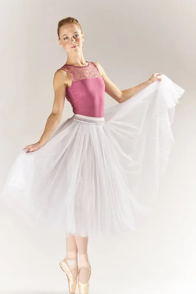 Žena balerína v špičaté boty a v tutu na lehkém pozadí představuje pózování nohy taneční model — Stock fotografie