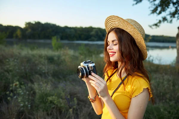 Wanita fotografer dengan kamera di tangannya tersenyum bibir merah topi alam lanskap — Stok Foto