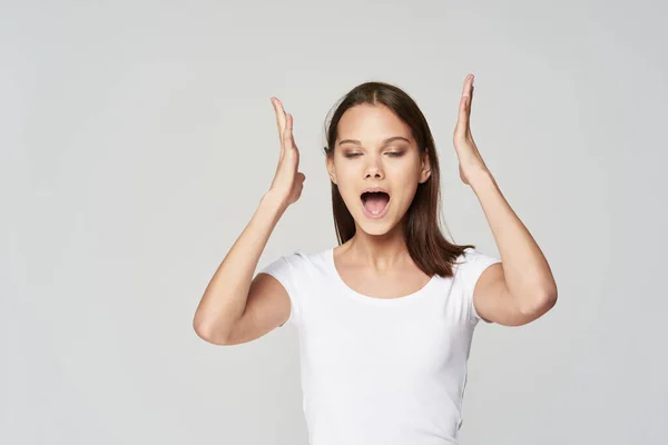 Ragazza con la bocca aperta tenere le mani vicino testa emozioni bianco t-shirt studio — Foto Stock