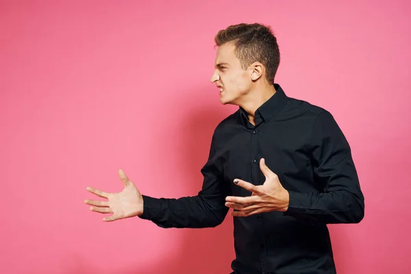 Man i svart skjorta gester med händer livsstil rosa isolerad bakgrund — Stockfoto