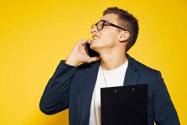 Zakenman op het werk het dragen van een bril en een jas op een gele achtergrond praten op de telefoon werknemer model — Stockfoto