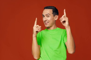 Neşeli yeşil tişörtler mavi izole edilmiş arka planda işaret parmaklarını gösteriyor 