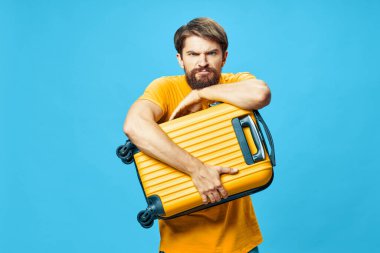 Ellerinde bavulla gücenmiş bir adam yüzünü buruşturmuş. 