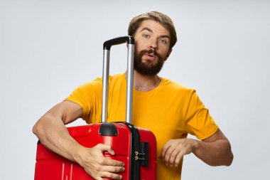 Kırmızı bavullu ve sarı tişörtlü adam. 