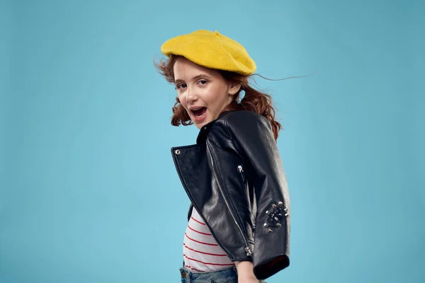 Mooi meisje met een zwart jasje en een gele hoed op haar hoofd rood haar model blauw achtergrond — Stockfoto