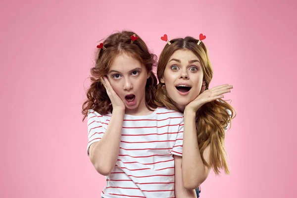 Meninas felizes com jóias na moda em suas cabeças em um fundo rosa divertido vista cortada de irmãs — Fotografia de Stock