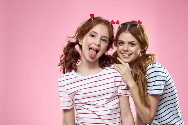 Ευτυχισμένα κορίτσια με μοντέρνα κοσμήματα στο κεφάλι τους σε ένα ροζ φόντο διασκέδαση περικοπή άποψη των αδελφών — Φωτογραφία Αρχείου