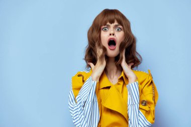 Korkak bir kadın, ağzı açık ve mavi çizgileri olan şık sarı bir ceket.