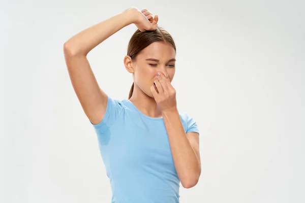 Frau mit verschwitzter Achselhöhle bedeckt Nase schlechte Geruchshygiene — Stockfoto