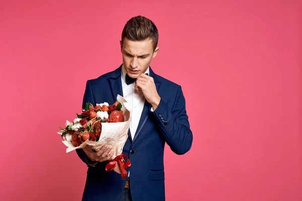 romantic man with bouquet of flowers and in bow tie on pink background cropped view
