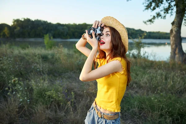 Женщина фотографирует природу в шляпе, красные губы — стоковое фото