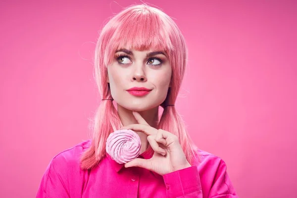 Mujer bonita con una camisa rosa con una galleta en la mano y una peluca — Foto de Stock