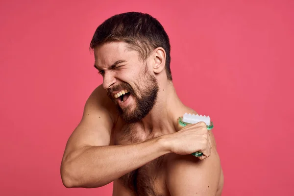 Man met blote schouders lichaam massager huidverzorging roze achtergrond — Stockfoto