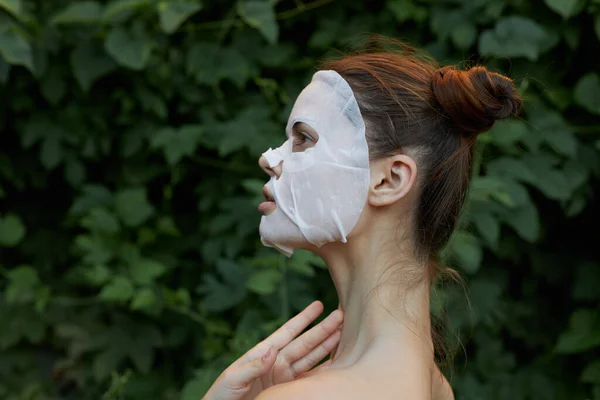Όμορφη γυναίκα λευκή μάσκα φροντίδα του δέρματος πράσινα φύλλα στο παρασκήνιο — Φωτογραφία Αρχείου