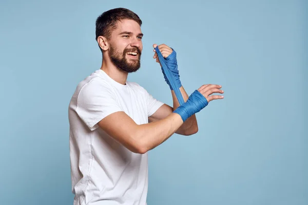 Sport uomo in bianco t-shirt boxe bende sulle mani blu isolato esercizio di fondo allenamento — Foto Stock