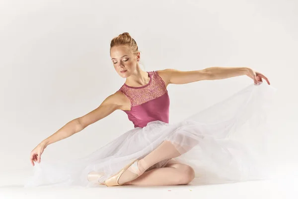 Mulher bailarina em sapatos pointe e em um tutu em um fundo leve posa posando pernas dança modelo — Fotografia de Stock