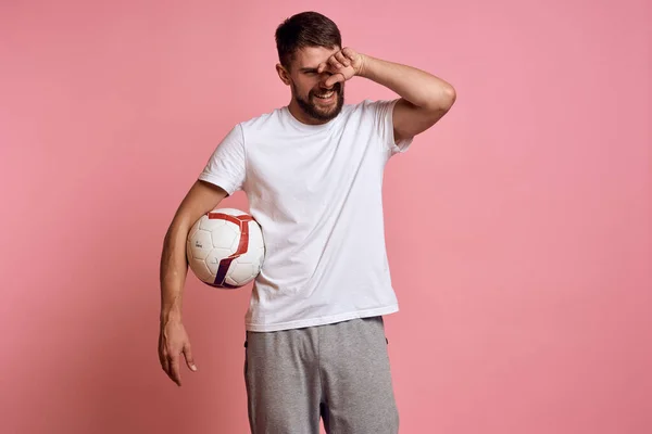 Uomo con un pallone da calcio su sfondo rosa energia gesticolare con le mani allenatore emozioni modello — Foto Stock