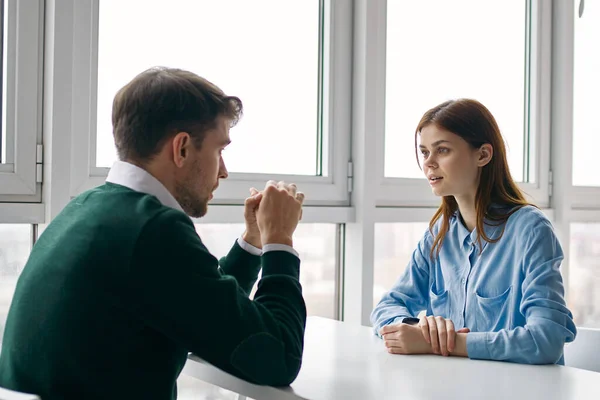 Vrouw kijkt met verbazing naar de man aan de tafel binnen — Stockfoto