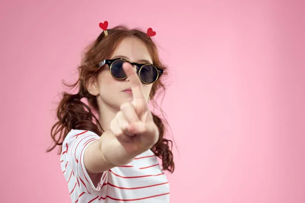 Aranyos lány napszemüveg csíkos t-shirt életmód szórakoztató stílus rózsaszín háttér — Stock Fotó