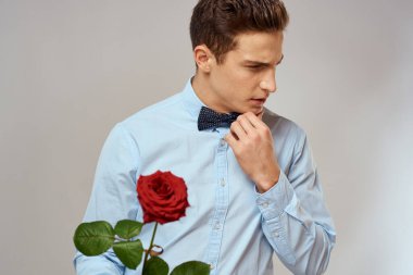 Kırmızı gül ve açık renk pantolon giyen romantik bir adam.