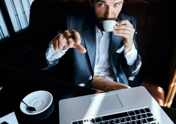 Uomo d'affari seduto in un caffè di fronte a un computer portatile con una tazza di caffè lavoro tecnologia stile di vita — Foto Stock