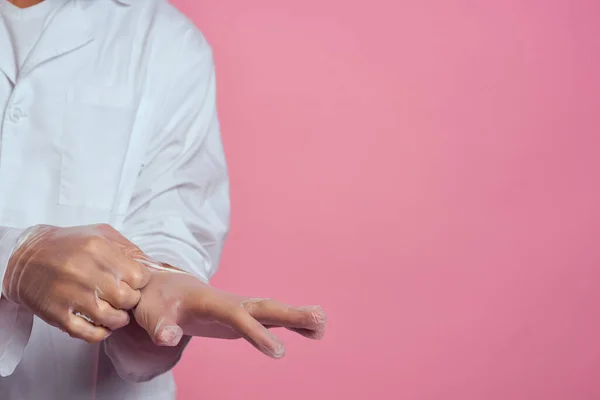 Manos bata médica en guantes transparentes fondo rosa vista recortada —  Fotos de Stock