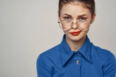 Mavi gömlekli ve gözlüklü duygusal kadın portresi parlak makyaj modeli arka plan kırpılmış görünüm kopyala