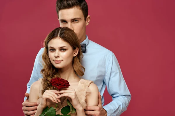 Hombre y mujer enamorados con una flor roja sobre un fondo rosa abrazarse Copiar espacio —  Fotos de Stock