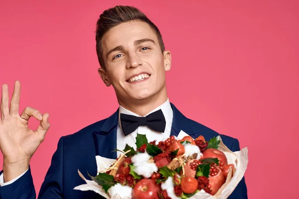 romantic man with bouquet of flowers and in bow tie on pink background cropped view