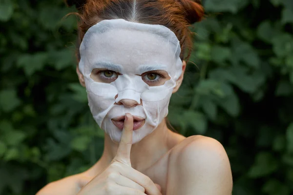 Portret dziewczyny palec przy ustach prośba o ciszę biała maska kosmetologia — Zdjęcie stockowe