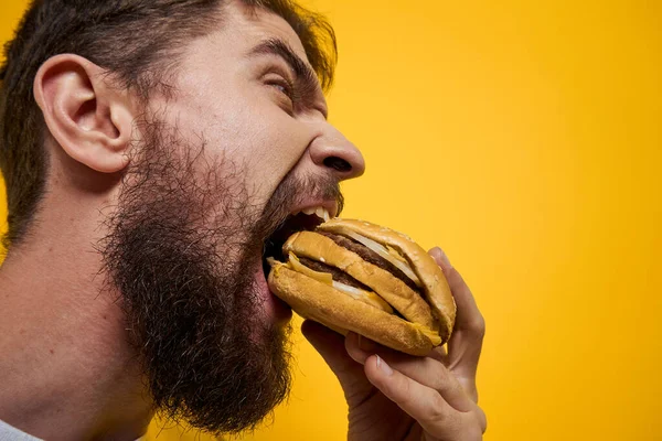 Mann mit Hamburger in den Händen von Fast-Food-Diät weißes T-Shirt Nahaufnahme gelber Hintergrund — Stockfoto